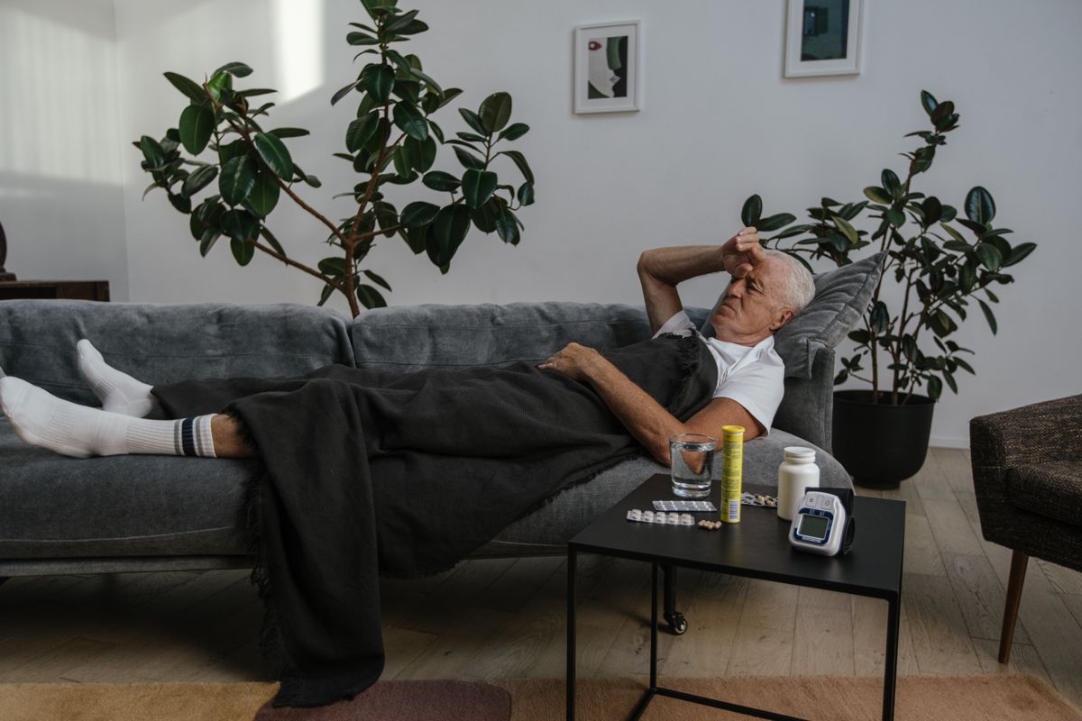 Man recovering at home on the couch with medication on the side table